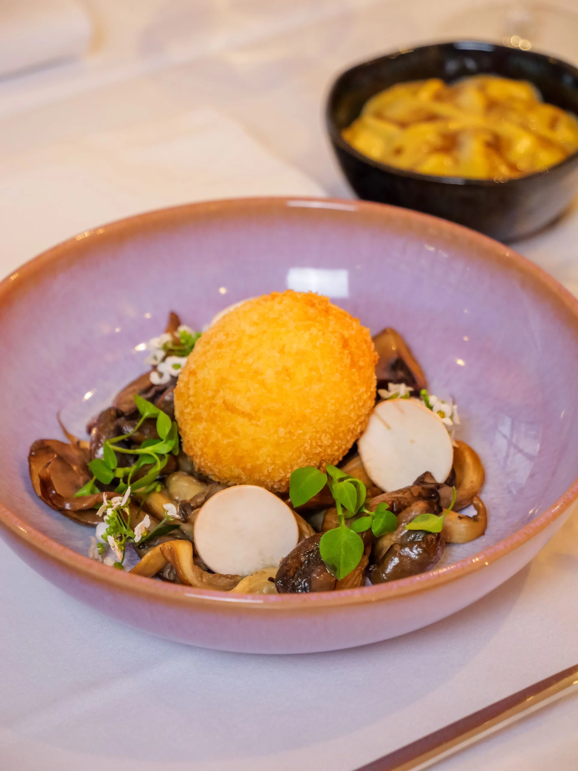 Photo d'une entrée comprenant un oeuf pané sur un sauté de champignons et légumes