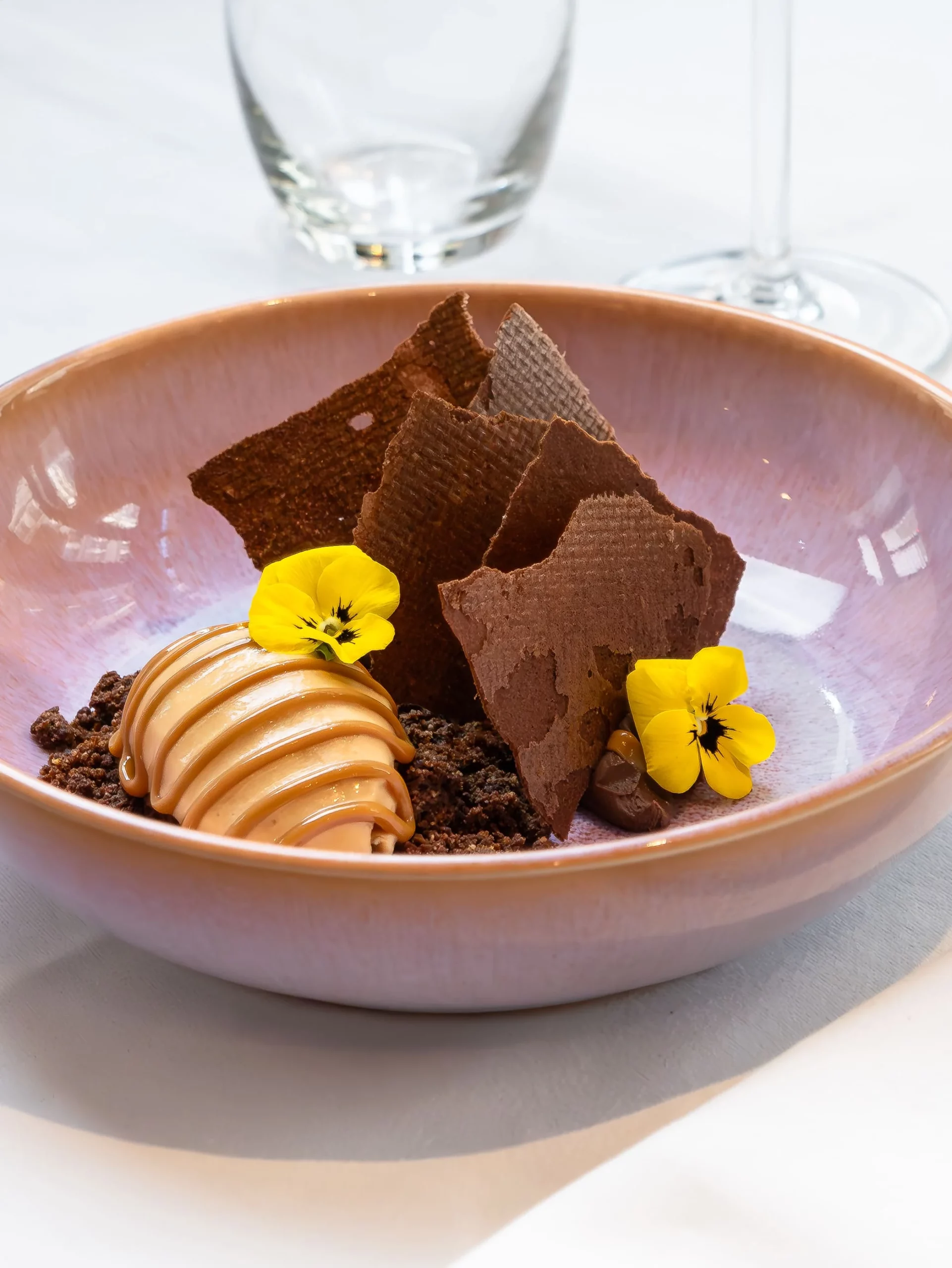 Photo d"une assiette à dessert, avec une glace et des feuilles de biscuit au chocolat dressés dessus